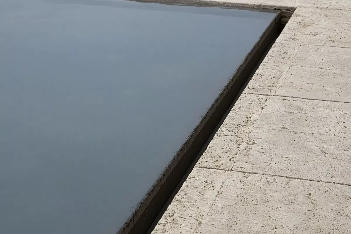 平静的水面通过池沿窄缝与石材甲板相接